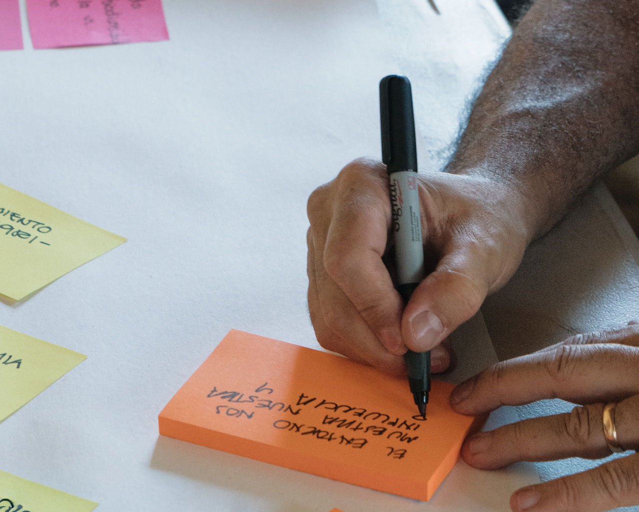 Participante escribiendo una idea en una nota adhesiva durante un taller sprint